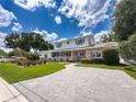 View of a two story brick home with a spacious driveway, green lawn, and manicured garden at 75 N Canal Dr, Palm Harbor, FL 34684