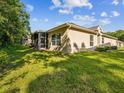 View of home's backyard with lush green grass and screened in patio at 7616 Wimpole Dr, New Port Richey, FL 34655