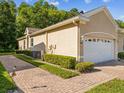 Side view of home's exterior featuring a well-manicured lawn, garage, and partial brick driveway at 7616 Wimpole Dr, New Port Richey, FL 34655