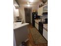 Functional kitchen with white cabinets, black appliances, and a view into the hallway at 8008 La Serena Dr, Tampa, FL 33614
