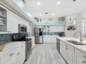 Bright kitchen featuring white cabinets, stainless steel appliances, and a stylish blue backsplash at 8137 Morning View Dr, Hudson, FL 34667