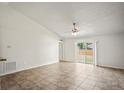Open living room with tile flooring, vaulted ceiling, a ceiling fan, and sliding glass doors to the backyard at 8461 Apple Orchard Rd, Spring Hill, FL 34608