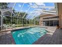 Sparkling blue swimming pool surrounded by a screened enclosure and brick paver deck at 888 Royal Birkdale Dr, Tarpon Springs, FL 34688