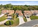 An aerial view showing the house with a tile roof, landscaping, driveway, and neighboring homes at 9355 French Quarters Cir, Weeki Wachee, FL 34613