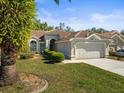 View of a well-maintained single-story home with lush landscaping, a concrete driveway, and tiled roof at 9355 French Quarters Cir, Weeki Wachee, FL 34613