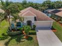 Charming single-story home with a well-manicured lawn, palm trees, and attached two-car garage at 10106 Tolman Dr, Hudson, FL 34667