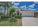Inviting home exterior with a two-car garage, lush lawn, and beautiful landscaping at 10106 Tolman Dr, Hudson, FL 34667
