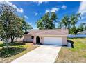 Aerial view of a cozy home with a well-kept lawn, attached garage, and a driveway with ample parking space at 10478 Laval St, Spring Hill, FL 34608