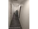 Hallway leading to laundry room, and featuring freshly painted walls and wood look flooring at 12116 Lamont Dr, Spring Hill, FL 34608