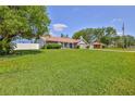 Spacious front yard view featuring a well-maintained lawn and mature trees surrounding the property at 12191 Monarco Ln, Spring Hill, FL 34609