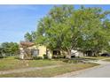 Landscaped front yard and home with a large tree providing shade at 12906 Sandburst Ln, Hudson, FL 34667