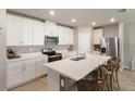 Bright kitchen featuring white cabinetry, stainless steel appliances, and a center island with seating at 13205 Arkendale St, Spring Hill, FL 34609
