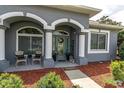 Inviting front porch with decorative columns and seating area, adding curb appeal to the home at 13524 Knotty Ln, Hudson, FL 34669