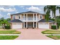 Traditional two-story home with a brick driveway, three-car garage, and manicured landscaping at 15906 Prince William Pl, Odessa, FL 33556