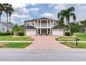 Stately two-story home with a brick driveway, white columns, three-car garage, and lush landscaping at 15906 Prince William Pl, Odessa, FL 33556