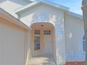 Covered front entry of a home with an arched ceiling, inset windows, and a white door at 19855 Ellendale Dr, Land O Lakes, FL 34638