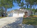 Charming single-story home with a three-car garage and well-maintained landscaping, under a bright blue sky at 19855 Ellendale Dr, Land O Lakes, FL 34638