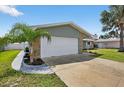 Side view of a single Gathering home showing the two-car garage, stone accents, and palm tree at 2175 Edythe Dr, Dunedin, FL 34698