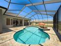 Enclosed pool area with a kidney-shaped pool, brick patio, and view of the surrounding backyard at 3464 Misty View Dr, Spring Hill, FL 34609