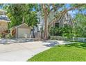 View of the side of a home including an oversized detached garage with updated doors and a well-manicured lawn at 520 Lafayette Blvd, Oldsmar, FL 34677