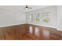 Living room with wood floors, three windows, and a ceiling fan at 658 Siren Wind Ln, Clearwater, FL 33756