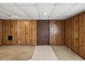 Finished basement area with door, featuring wood-paneled walls and tile flooring at 7012 Ponderosa Dr, Tampa, FL 33637
