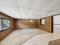 Spacious basement featuring wood-paneled walls, tiled flooring, and cozy carpet at 7012 Ponderosa Dr, Tampa, FL 33637