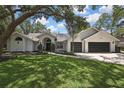 The traditional home boasts a pristine lawn, lush trees and a two-car garage at 7233 Royal Oak Dr, Spring Hill, FL 34607