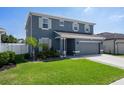 Well-maintained two-story home with a gray facade, complemented by lush landscaping and a two-car garage at 733 Old Windsor Way, Spring Hill, FL 34609