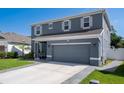 Well-maintained two-story home with a gray facade, complemented by lush landscaping and a two-car garage at 733 Old Windsor Way, Spring Hill, FL 34609
