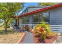 Landscaped front yard with colorful plants, walkway to front door and gray exterior with a red trim at 800 N Walton Ave, Tarpon Springs, FL 34689