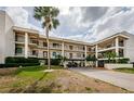 A condo building with balconies and a covered drive-through showcases tropical landscaping and a bright, sunny ambiance at 8210 Aquila St # 218, Port Richey, FL 34668