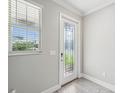Bright foyer featuring a decorative glass door, a window with blinds, and stylish gray wood-look tile flooring at 8630 Campus Woods Way, New Port Richey, FL 34655