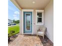 Inviting front porch with a decorative glass door, window, and chair for relaxing, complete with brick pavers at 8630 Campus Woods Way, New Port Richey, FL 34655
