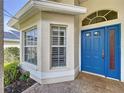 Inviting home entrance with a bright blue front door, detailed trim, and large windows for natural light at 1006 Sweet Jasmine Dr, Trinity, FL 34655