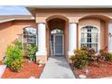 Inviting front entrance featuring a charming walkway, manicured landscaping, and stylish architectural columns at 12040 Penzance Ln, New Port Richey, FL 34654