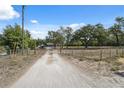 Long gravel driveway leading to a home with mature trees and a secure gated entrance for added privacy at 14545 Battenwood Dr, Spring Hill, FL 34610