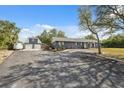 Exterior view of the house showing a large driveway and additional garage/barn on this expansive property at 14545 Battenwood Dr, Spring Hill, FL 34610