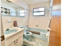 Retro bathroom with a blue toilet, sink, and tub, complemented by classic white and blue wall tiles at 4333 Baden Dr, Holiday, FL 34691