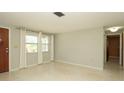 Spacious room featuring terrazzo floors, natural light, a view of the front yard, and an open doorway at 5018 Sherwood Dr, New Port Richey, FL 34652