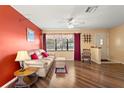 Cozy living room features hardwood floors, a ceiling fan, and a large window with natural light at 6805 Washington St, New Port Richey, FL 34652