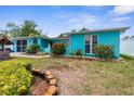 Charming turquoise home featuring an unmanicured lawn and colorful landscaping at 9015 Mark Twain Ln, Port Richey, FL 34668