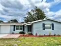Charming single-story home showcasing blue siding, brick walkway and well-maintained landscaping at 9034 Cochise Ln, Port Richey, FL 34668