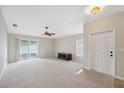 Spacious living room with neutral carpet, ceiling fan, and sliding glass door to the screened in patio at 9048 Southern Charm Cir, Brooksville, FL 34613