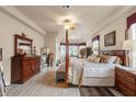 Spacious main bedroom offers a stylish four-poster bed, wood floors, and comfortable sitting area at 9245 Grand Cypress Dr, Spring Hill, FL 34613