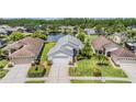Aerial view of a single-story home with a two car garage, lush lawn, and tranquil lake in the backyard at 1053 Winding Willow Dr, Trinity, FL 34655