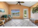 Cozy sun room with tile floors, vaulted ceilings, wicker furniture, and a scenic lake view at 1053 Winding Willow Dr, Trinity, FL 34655