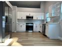 Modern kitchen featuring stainless steel appliances, white cabinets and hardwood floors at 10906 Carnelian Ln, Riverview, FL 33578