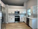 Modern kitchen featuring stainless steel appliances, white cabinets and hardwood floors at 10906 Carnelian Ln, Riverview, FL 33578