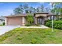Inviting single-story home with a two-car garage, manicured landscaping, and an arched entryway at 11443 Marsh Creek Ct, New Port Richey, FL 34654